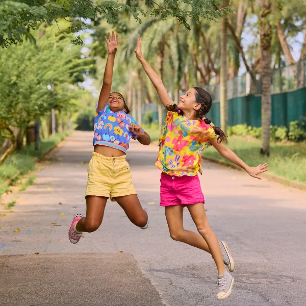 Two foster care teens jumping up for a tree branch.